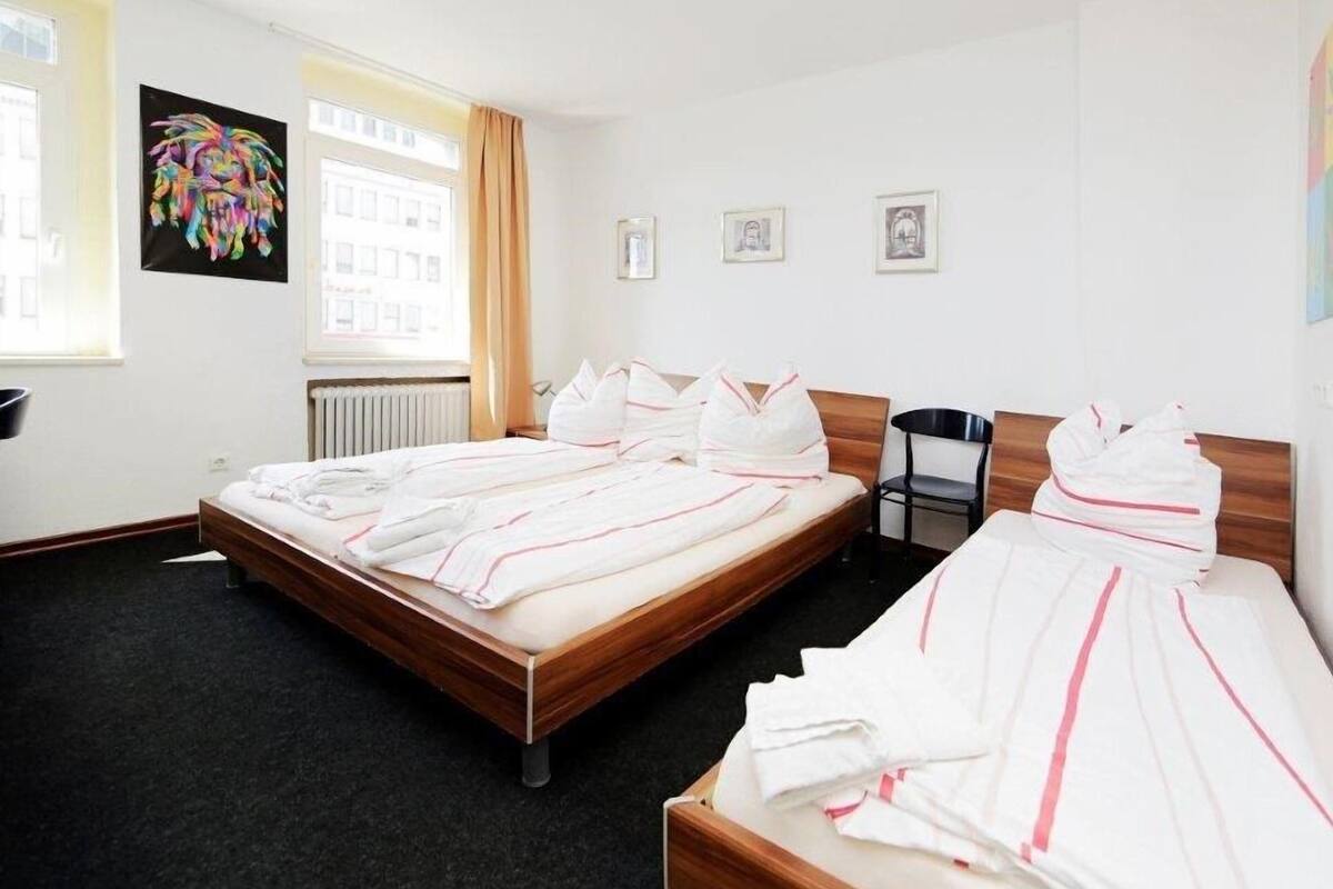 Hotellihuone, jossa on kaksi sänkyä, tuoli ja taideteoksia seinillä.