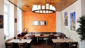 Ein Restaurant mit Holzbalkendecke, orangefarbenen Wänden und Fliesenboden mit sechseckigem Muster.