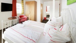 Ein Hotelzimmer mit einem Bett, einem Fernseher, einem roten Sessel und einem Holzschrank.