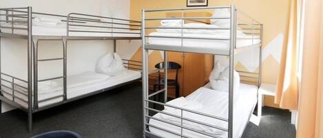 A dormitory room with bunk beds, a desk, and a chair.