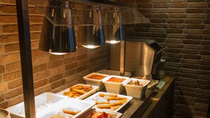 Uma mesa de buffet com diversos alimentos e uma pilha de pratos.
