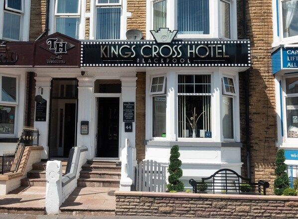 The Kings Cross Hotel entrance with a traditional facade, a signboard, and a staircase leading to the entrance. - The Kings Cross Hotel (Blackpool)