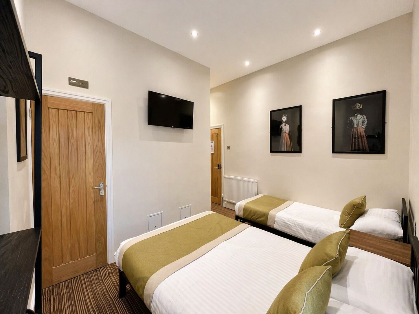 A hotel room with two beds, a TV, and two framed pictures on the wall.