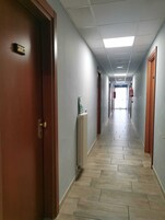 Un pasillo con puertas de madera, un radiador y suelo de baldosas.