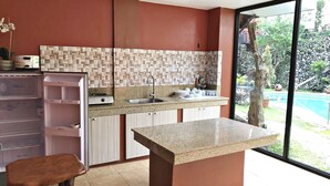 A modern kitchen with a granite countertop, a built-in sink, and a large window overlooking a garden. - Pura Vida Villas (Tagaytay)