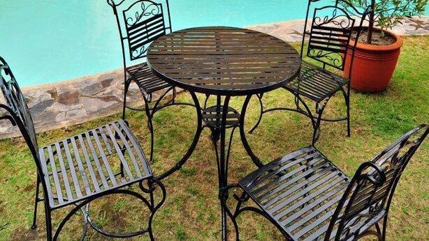 A pool area with a stone wall, a small waterfall feature, and outdoor seating. - Pura Vida Villas (Tagaytay)