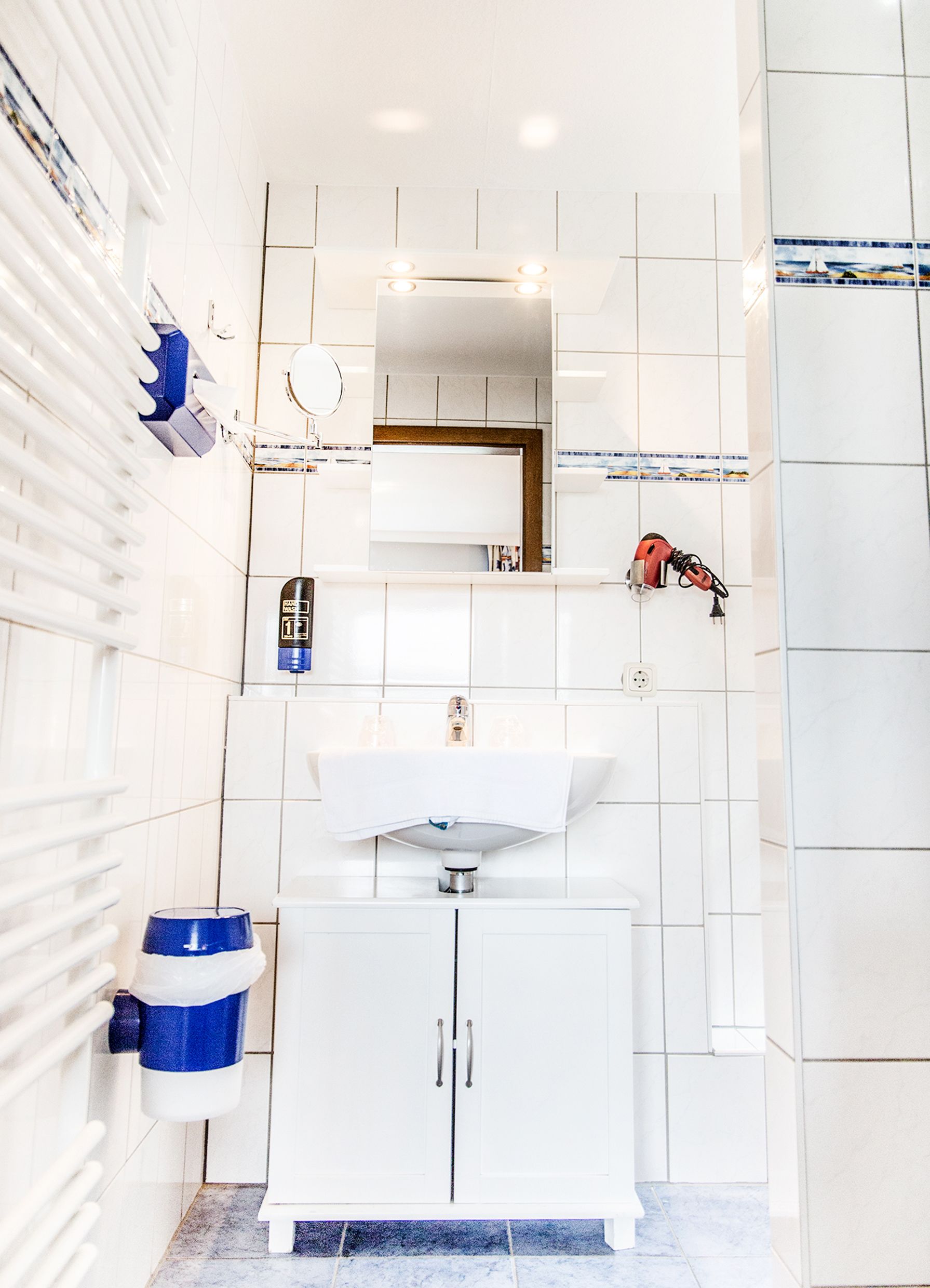 A modern bathroom with a white sink, mirror, and cabinet.