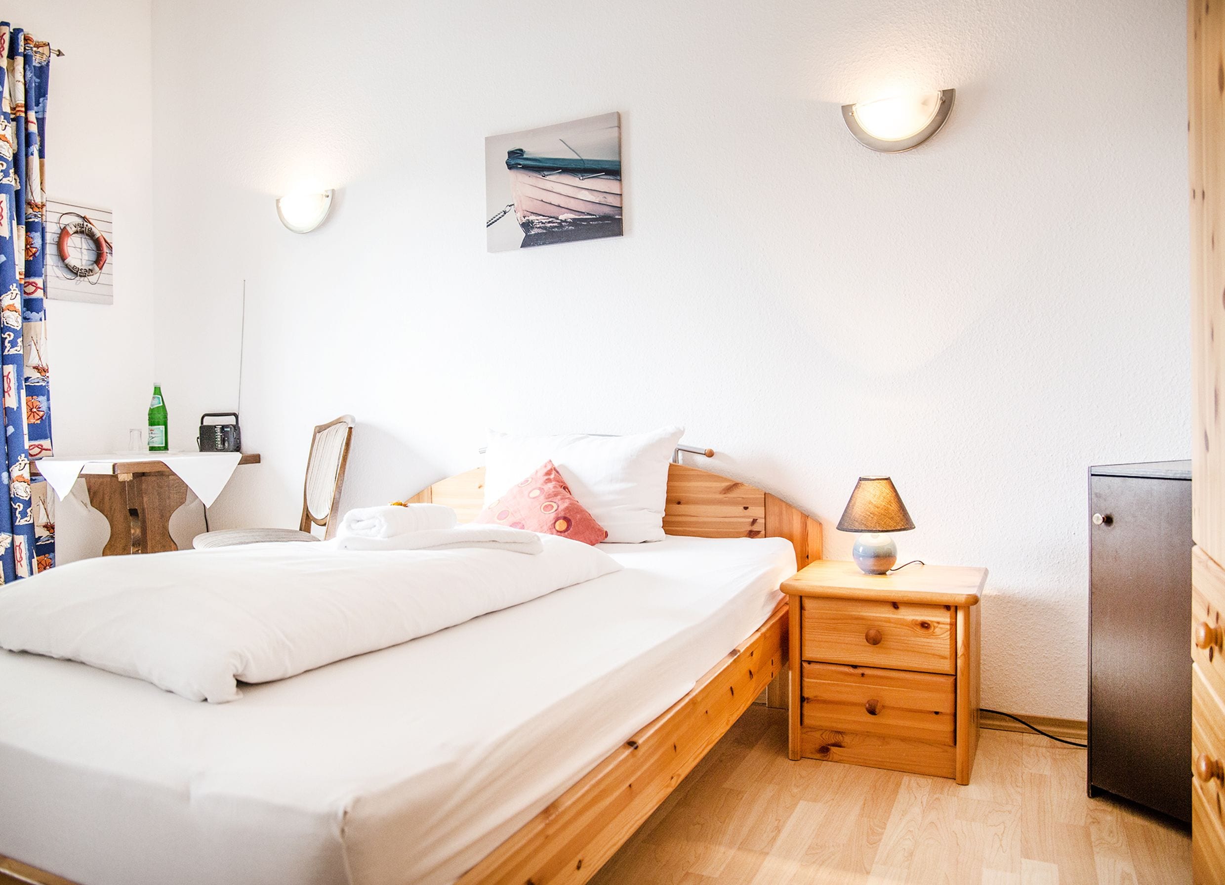 Un dormitorio ordenado con una cama de madera, mesitas de noche, una lámpara y un refrigerador.