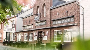 A row of brick buildings with signs for a hotel, a restaurant, and a beer hall. - Hotel Tum Stüürmann (Büsum)