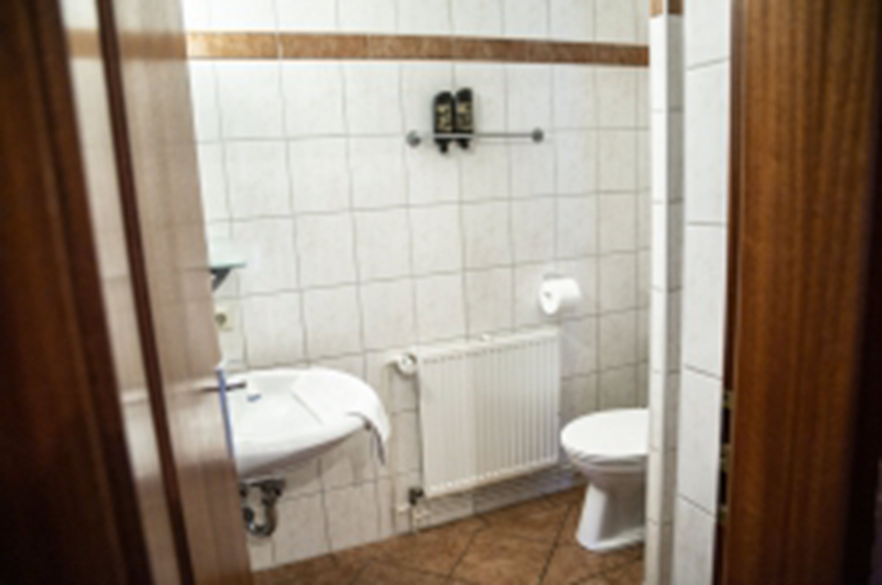 A small bathroom with a white sink, toilet, and a towel rack.