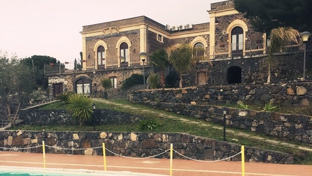 A swimming pool with a stone wall and a building in the background.