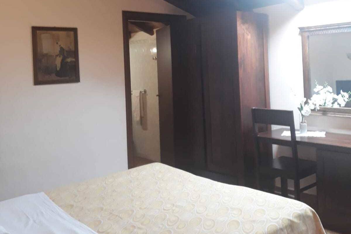 Une chambre à coucher avec un lit, une chaise, un bureau et un tableau accroché au mur.