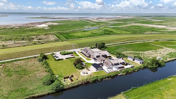 Una extensa propiedad con varias construcciones, un río y amplios campos verdes.