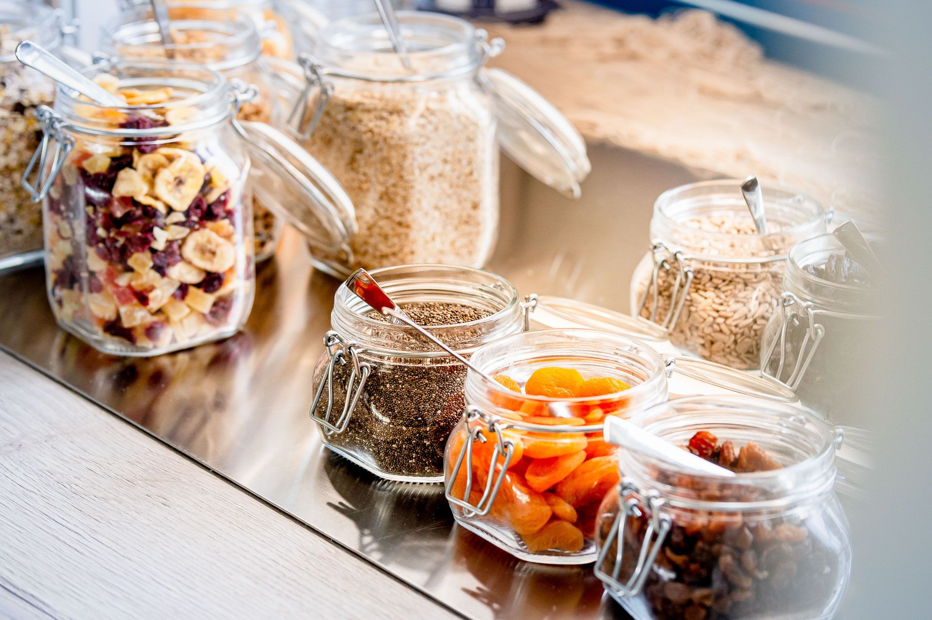 Several glass jars with various food items on a reflective surface.