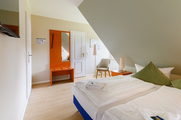 Una habitación de hotel con una cama, una silla, un escritorio y un espejo.