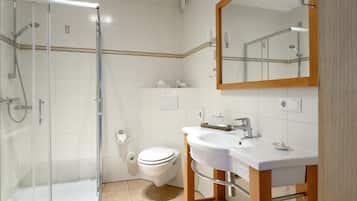 A modern bathroom with a glass-enclosed shower, a white toilet, and a vanity with a mirror.