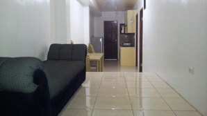 A living room with a sofa, a small table, and a kitchen area in the background.