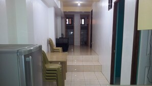 A compact kitchen with a refrigerator, a dining table with chairs, and a staircase leading to another room.