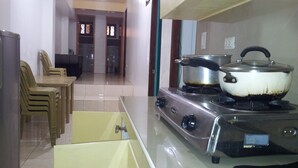 A kitchen with a stove, a sink, and a dining area with chairs.