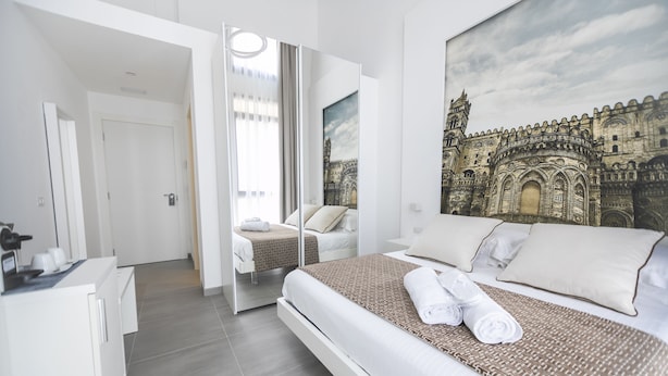 Moderni hotellihuone, jossa on suuri sänky, vaatekaappi, työpöytä ja suuri ikkuna.