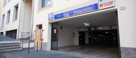 Entrada de um estacionamento com uma placa indicando 'Parcheggio Maqueda' e um lance de escadas visível.