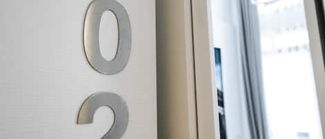 A hotel room with a bed, a window, and a door with the numbers "102" on it.