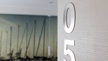 A modern hotel room with a large bed, a nightstand, and a wall with the numbers 105 visible.