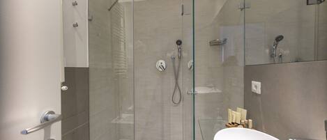 A modern bathroom with a glass-enclosed shower, a white bathtub, and a glass shower door.