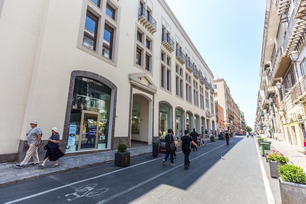 A street with buildings, a bike lane, and pedestrians.