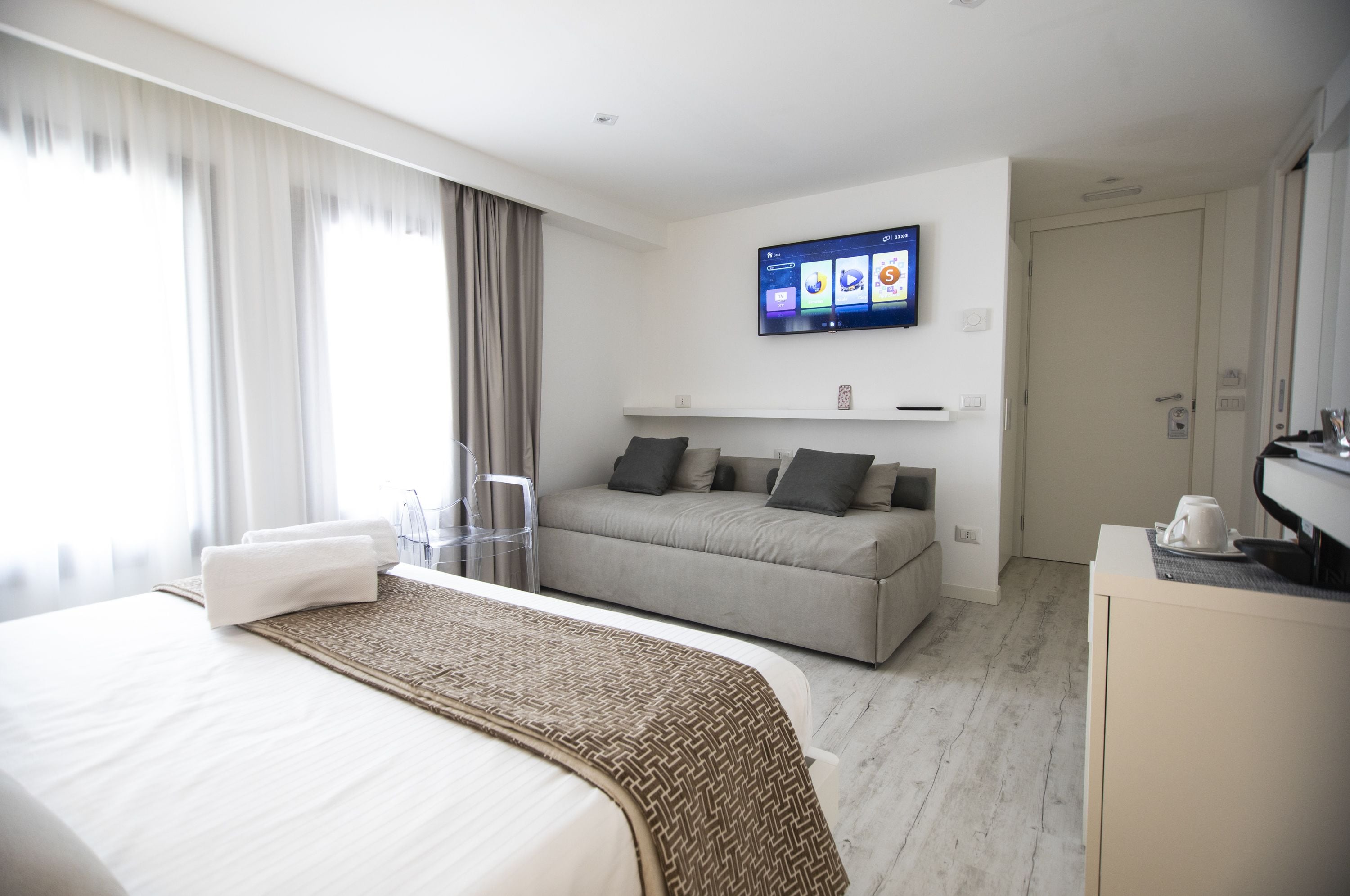 Une chambre d’hôtel moderne équipée d’un lit, d’un canapé, d’une télévision à écran plat et d’une machine à café.