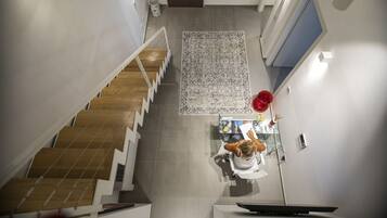 A modern interior with a staircase, a central rug, and a dining area.