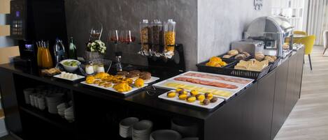 Montaje de bufé con diferentes alimentos, dispensadores de condimentos y una máquina de café.