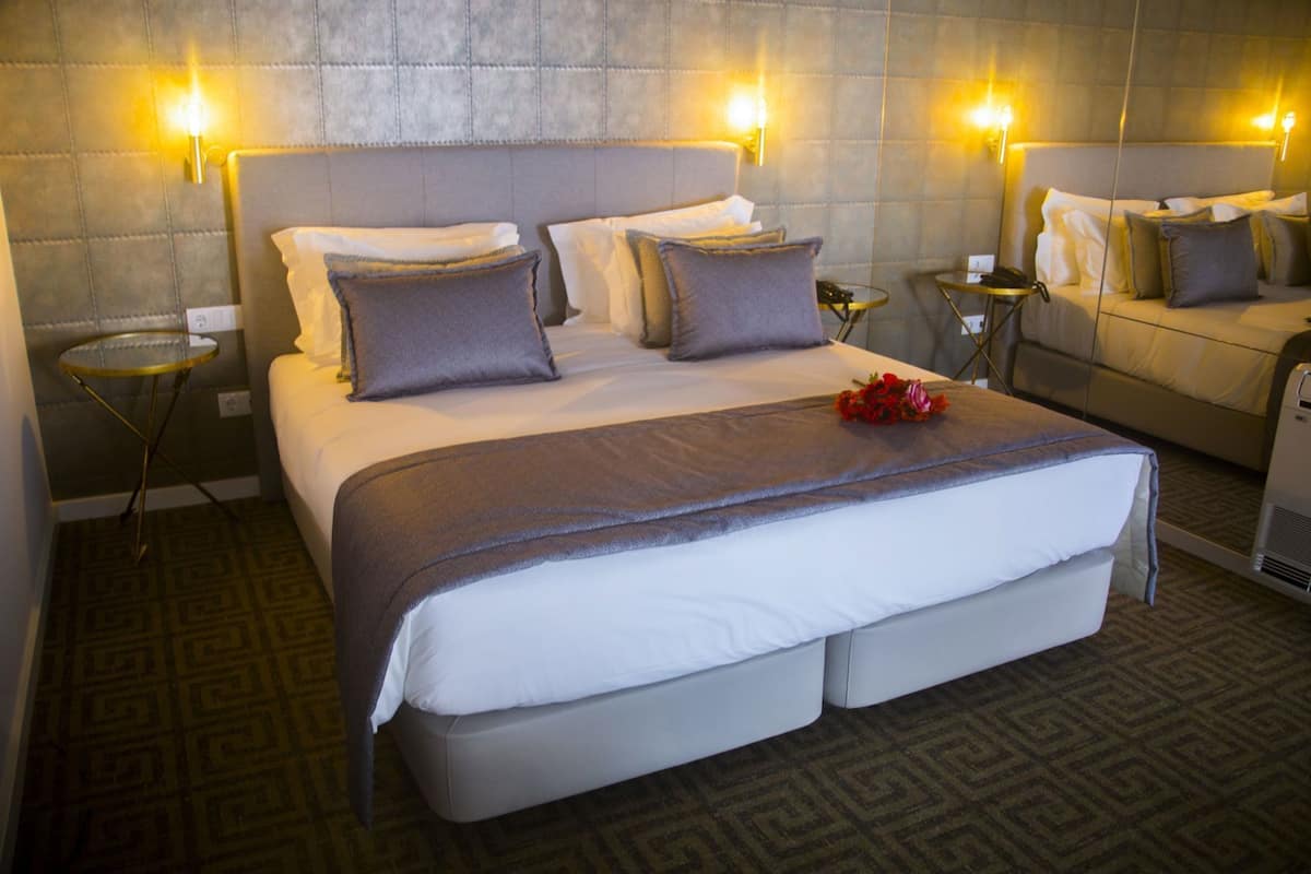 Ein Hotelzimmer mit einem großen Bett, zwei Nachttischen, einem kleinen runden Tisch und einem Sofa.