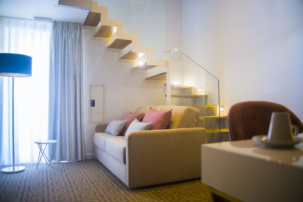 Ein modernes Wohnzimmer mit einer Couch, einem Couchtisch und einer Treppe mit Glastrennstäben.