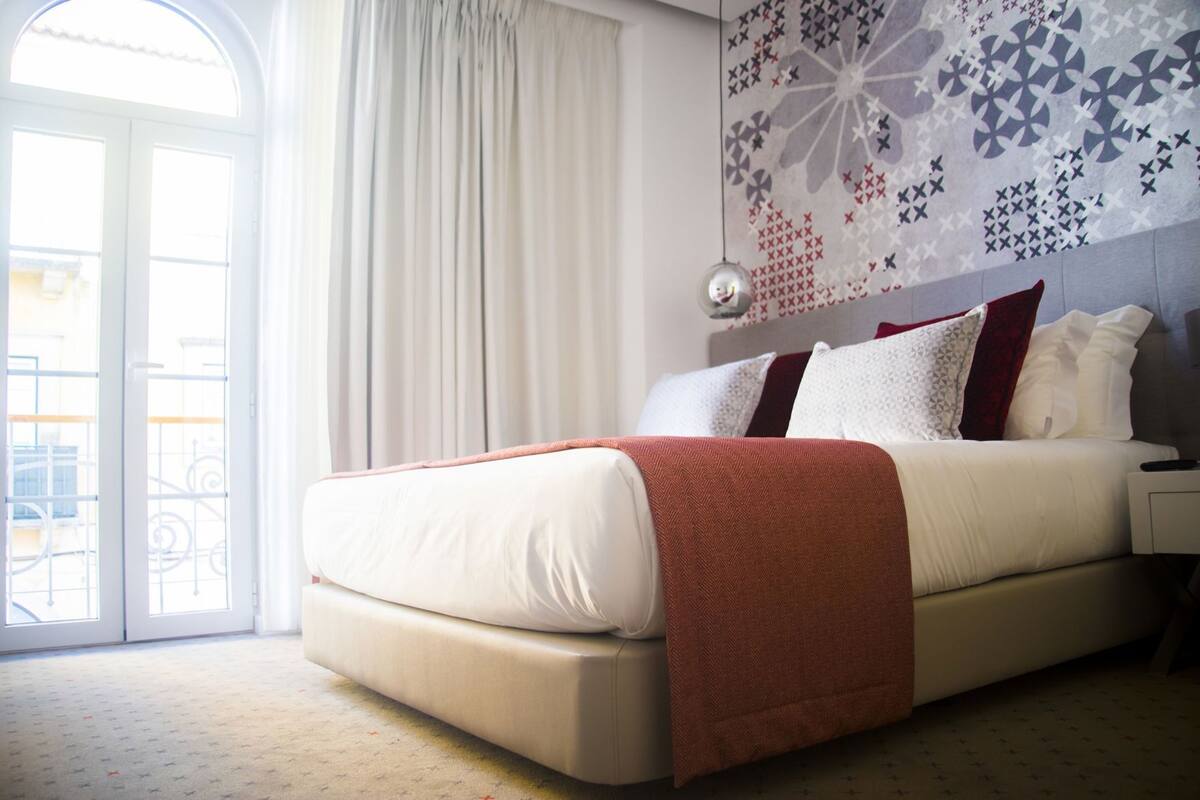 Ein Schlafzimmer mit Bett, Fenster und einer Wand mit Muster.