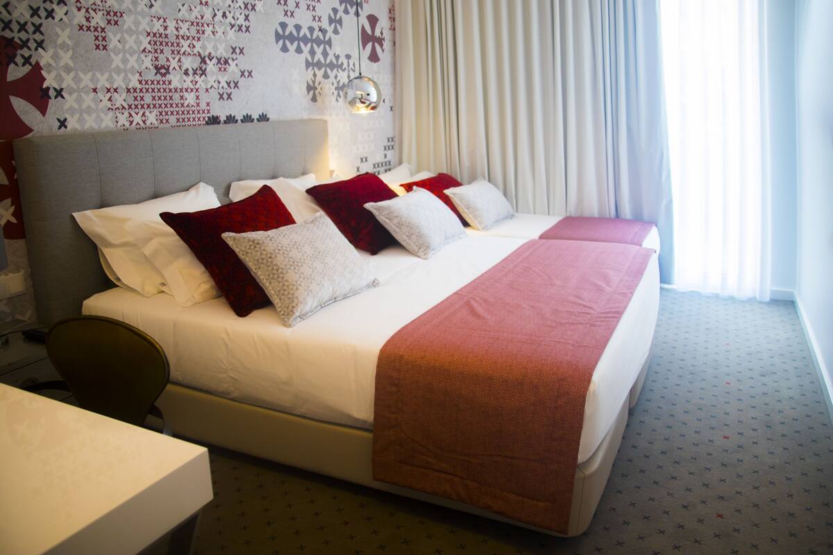Ein Hotelzimmer mit einem großen Bett, einem Schreibtisch und einer Wand mit Muster.