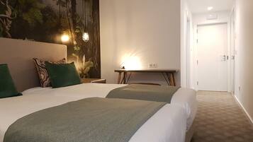 Une chambre d’hôtel avec deux lits, un bureau, une chaise, une décoration murale et une porte.