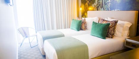 Habitación de hotel con dos camas, una mesita y una silla.