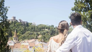 A couple overlooking a historic town with a prominent tower and castle in the background. - Thomar Boutique Hotel (Tomar)