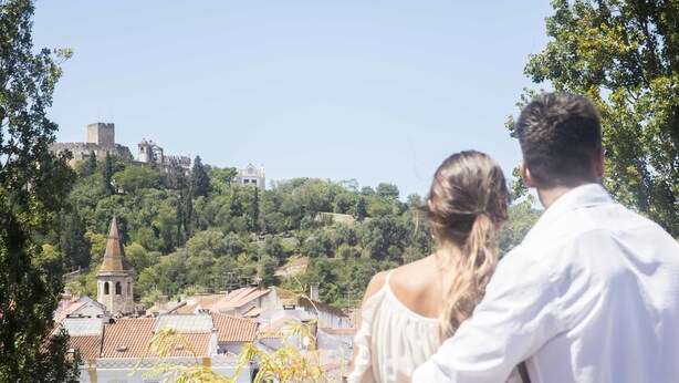 A couple overlooking a historic town with a prominent tower and castle in the background. - Thomar Boutique Hotel (Tomar)