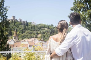 Una pareja contempla un pueblo histórico con una torre y un castillo destacados al fondo.