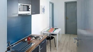 Una cocina compacta con microondas, lavamanos y encimera de madera.