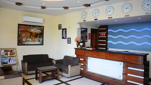 A lobby with a reception desk, sofas, a coffee table, and wall-mounted clocks. - Hotel Sarovar Regency (Amritsar)