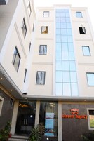 Un hotel de varios pisos con una llamativa fachada de vidrio y un letrero que dice Hotel Sarovar Regency.