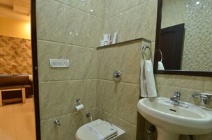 A bathroom with a marble wall, a sink, a mirror, and a towel rack.