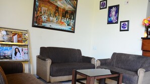A living room with two sofas, a coffee table, and a TV on a stand. - Hotel Sarovar Regency (Amritsar)