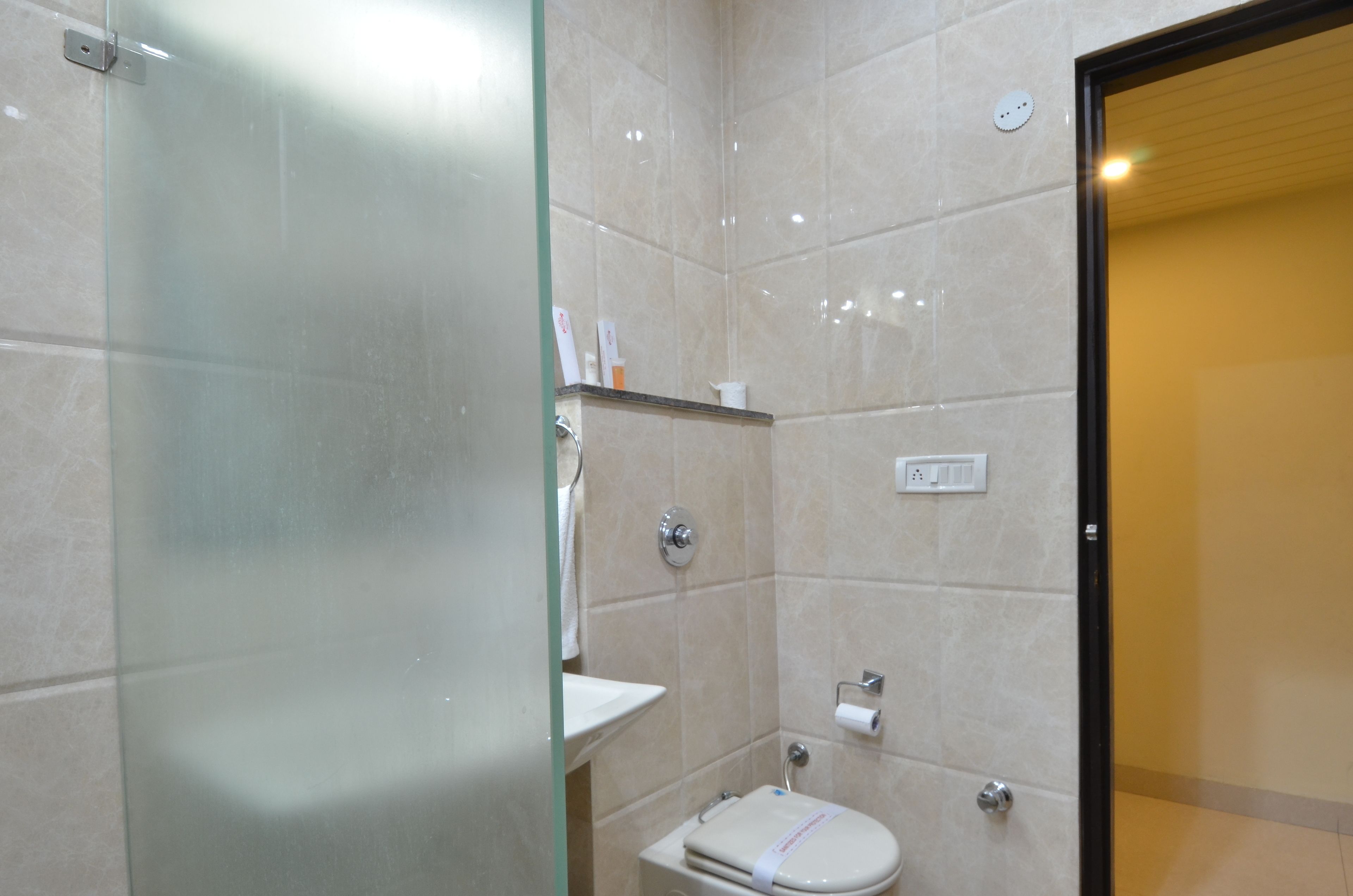 Un baño con cabina de ducha de vidrio, inodoro y lavamanos.