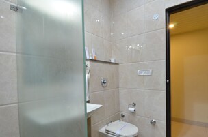 Un baño con cabina de ducha de vidrio, inodoro y lavamanos.
