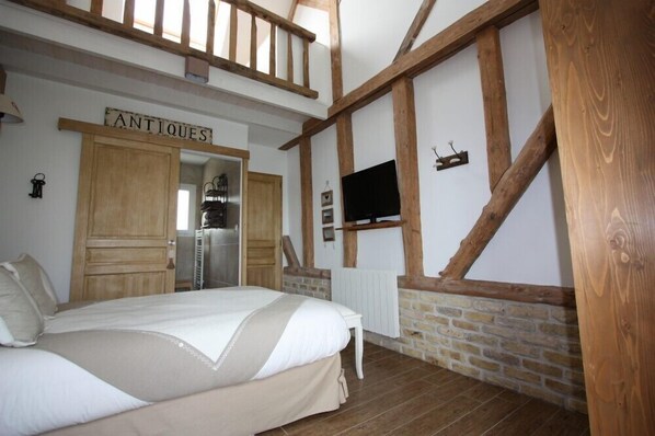 Un dormitorio con cama, vigas de madera, televisor y un letrero que dice 'ANTIQUE'.