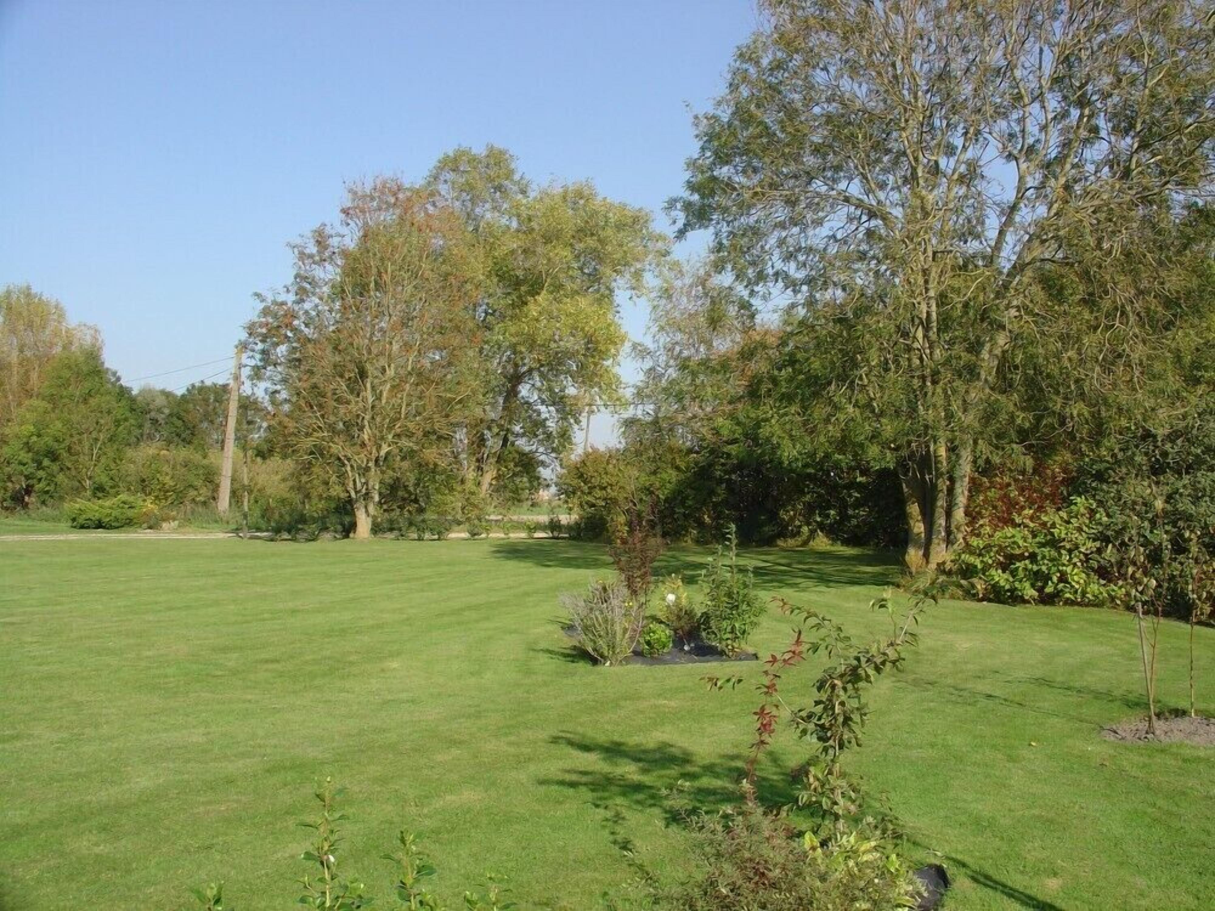 A well-maintained grassy area with trees and shrubs, likely a garden or park.